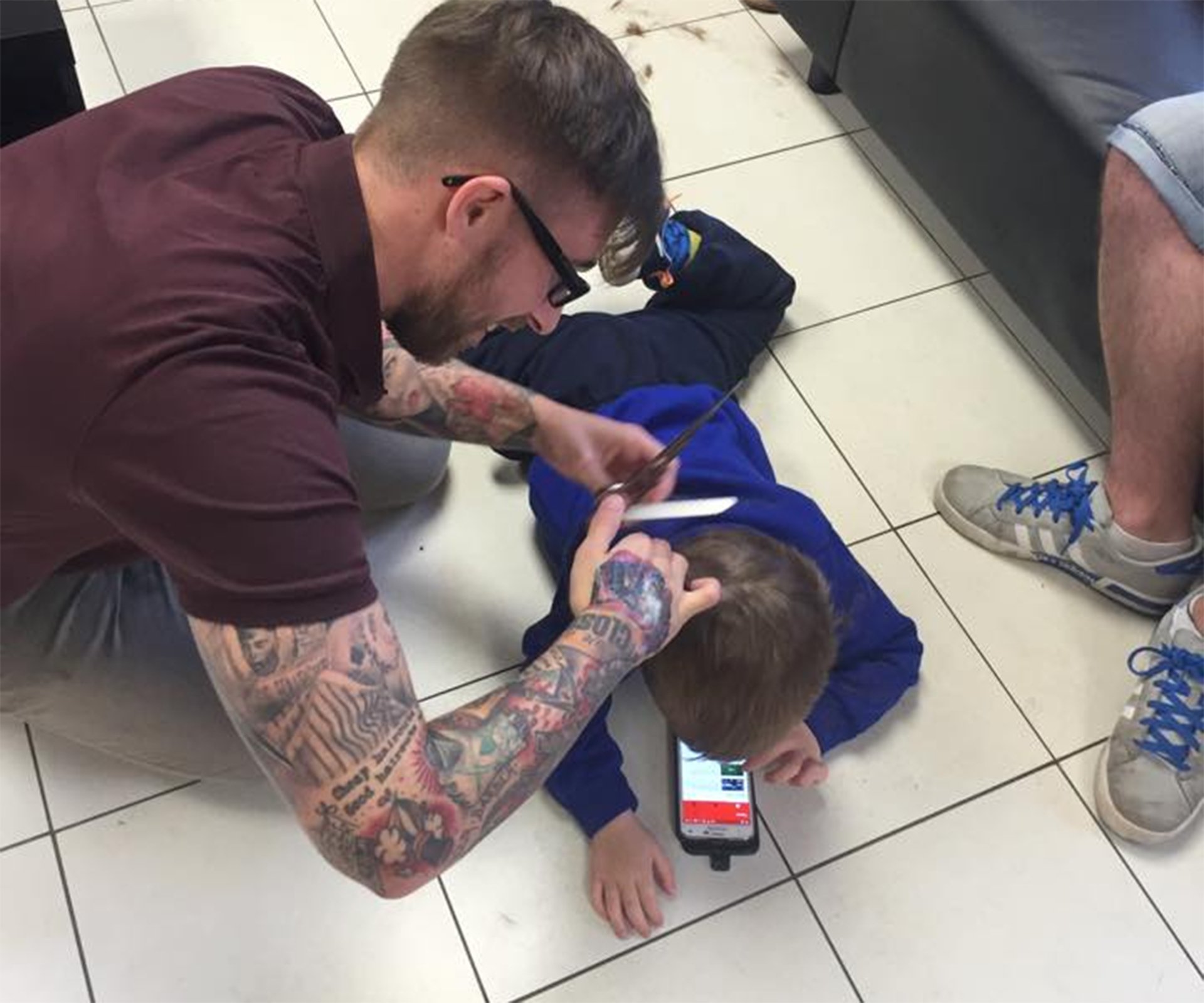 Barbeiro deita no chao para cortar o cabelo de um garoto autista 2